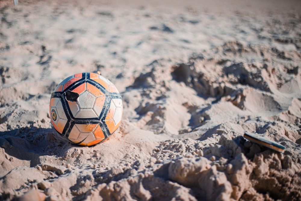 white and blue soccer ball on gray sand