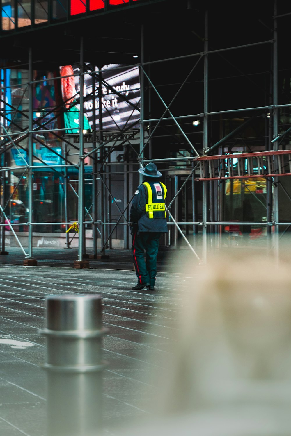 man in black and yellow adidas jacket standing on gray concrete floor