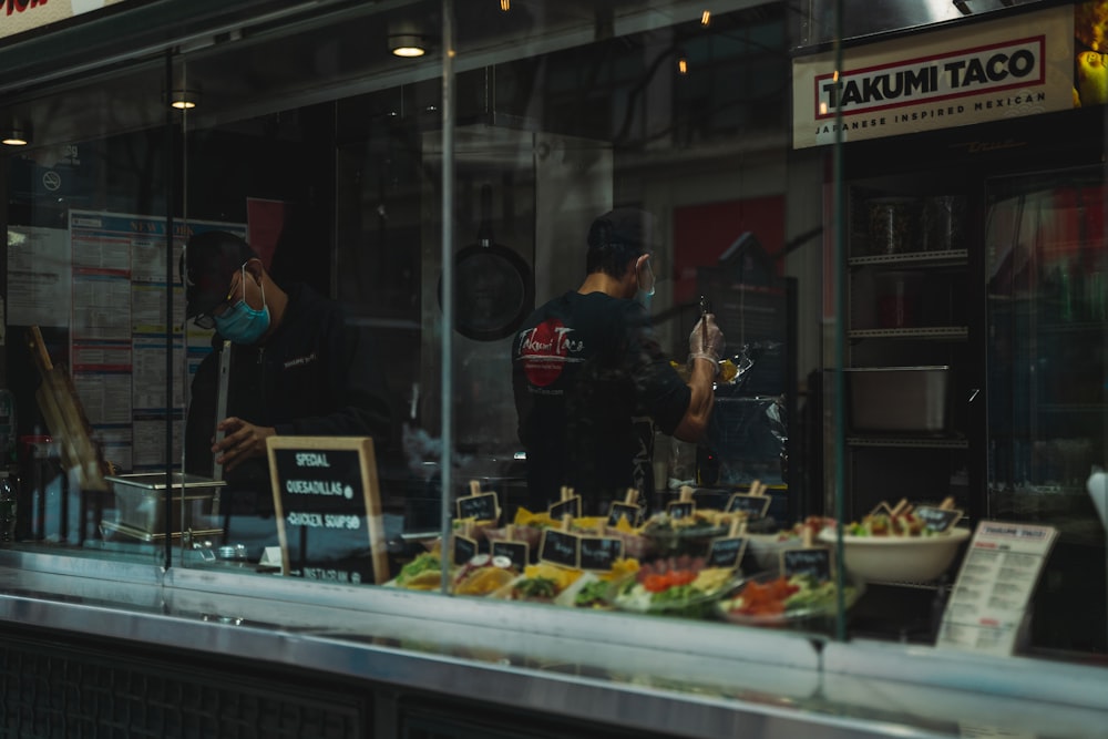 man in black t-shirt standing in front of food stall