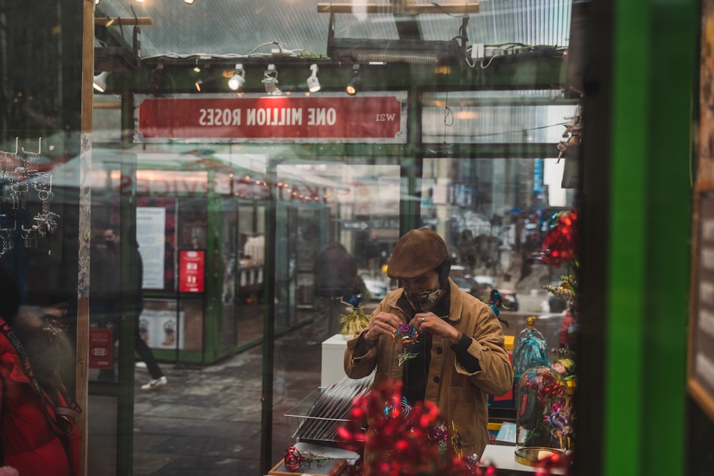 homme en chemise jaune debout près de fleurs rouges