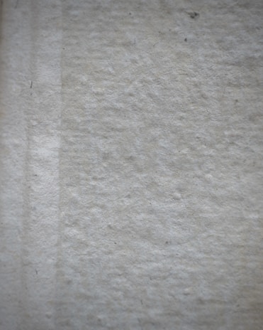 Close-up of a matte light gray surface with delicate linear patterns and soft gradients.