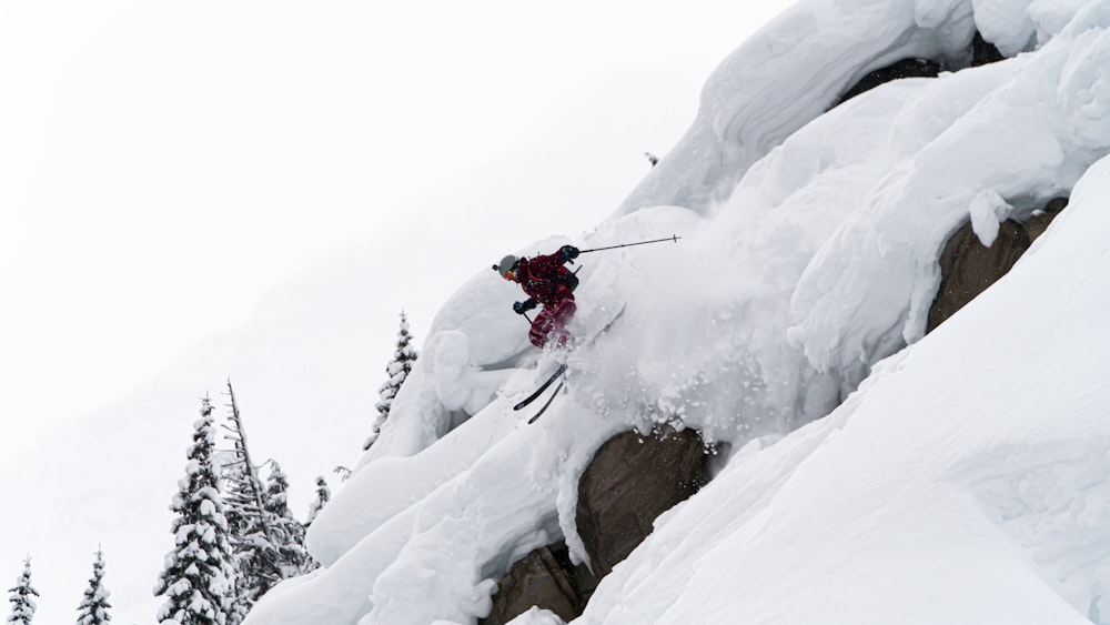 person in red jacket and black pants riding ski blades on snow covered mountain during daytime