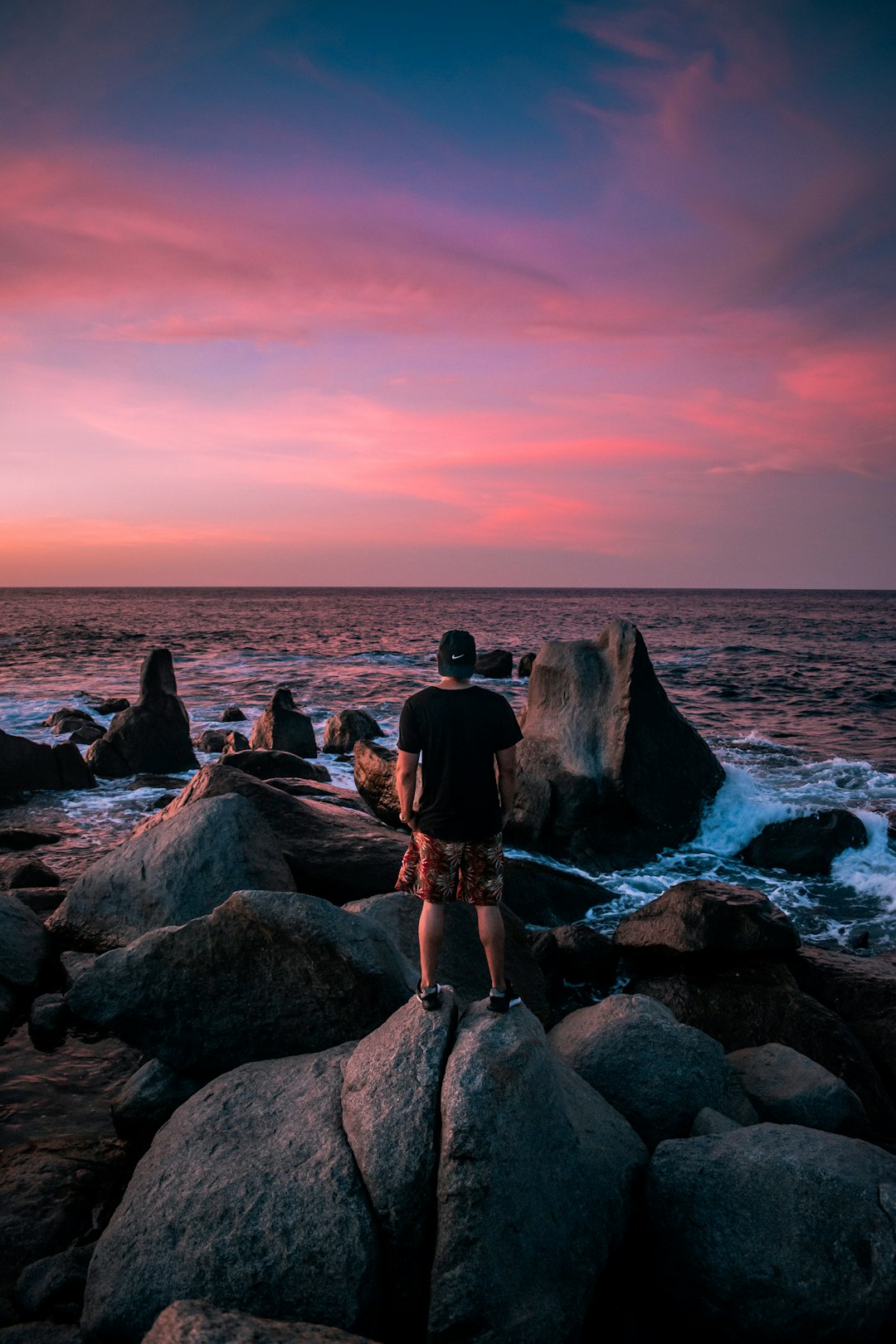 3 women sitting on rock near body of water during sunset