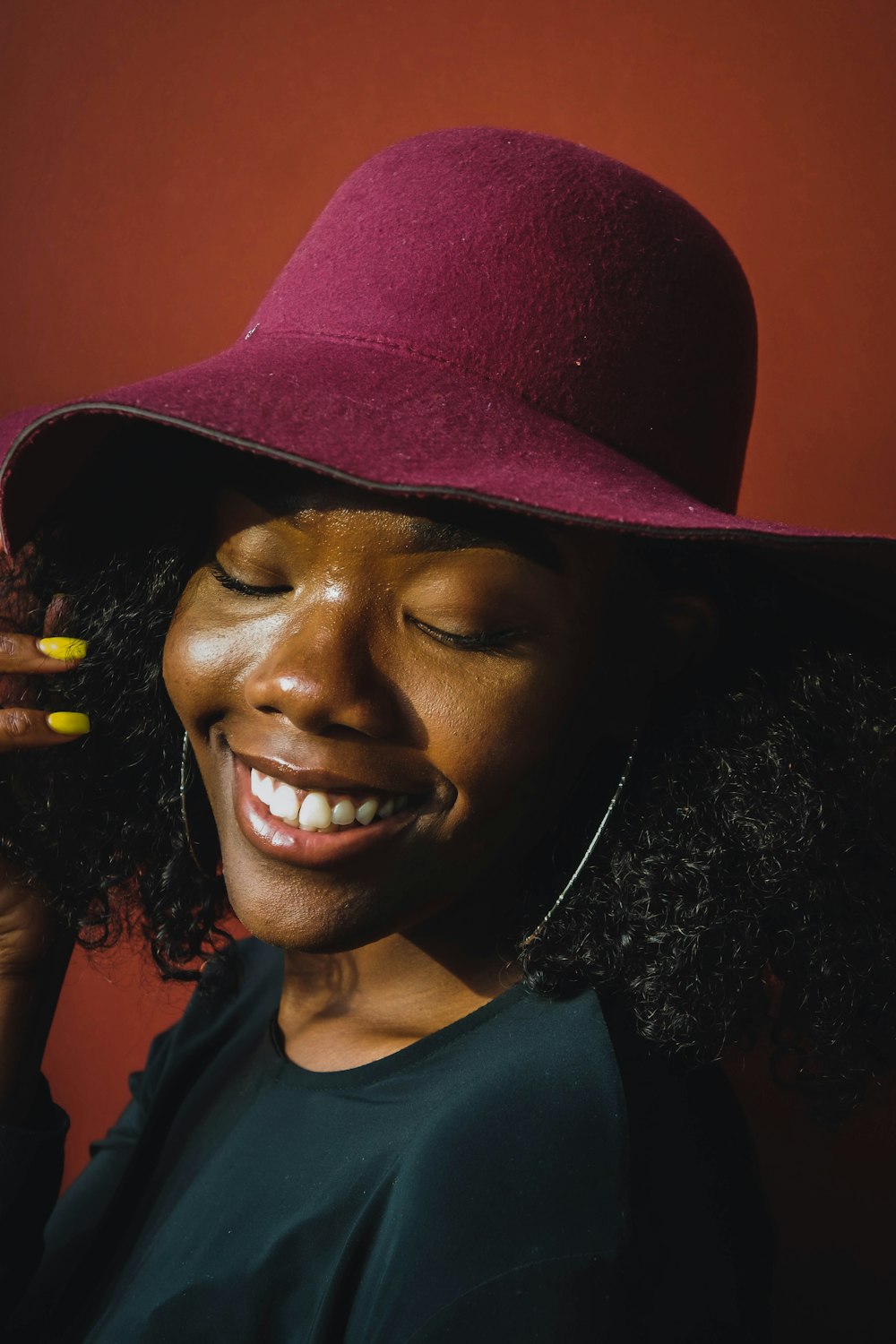 smiling woman in black shirt wearing brown hat