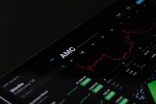 A digital stock trading interface with the focus on AMC Entertainment Holdings, Inc. The screen displays various financial data including stock prices, volume, and market cap. A red line graph shows stock performance over time and several buttons allow for different time frame selections like 1W, 1M, and 1Y. Various stock metrics appear in rows and columns.