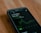 A smartphone displays stock market information, specifically for GameStop, highlighting the current price and a green graph indicating stock fluctuations.