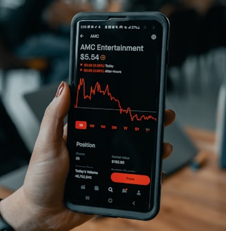 a person holding a cell phone with an amg entertainment app on the screen