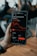 A hand holding a smartphone displaying a stock trading app screen. The app shows stock information for AMC Entertainment, including a line graph of its performance, current price, and trading options.