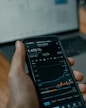 a person holding a cell phone in front of a laptop