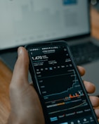 a person holding a cell phone in front of a laptop