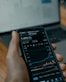 a person holding a cell phone in front of a laptop
