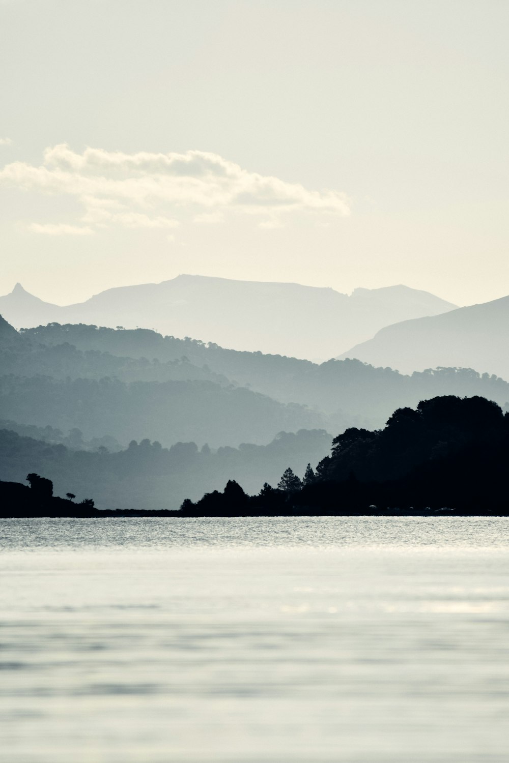 silhouette di montagna vicino allo specchio d'acqua durante il giorno