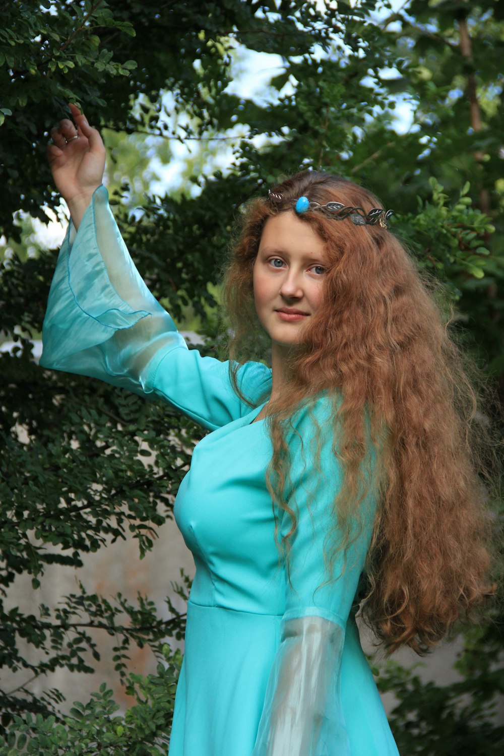 Mujer en camisa de manga larga verde azulado sosteniendo su cabello