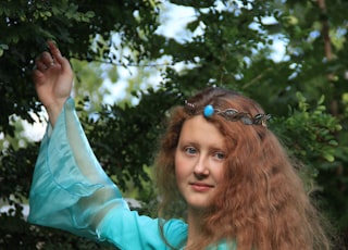 woman in teal long sleeve shirt holding her hair