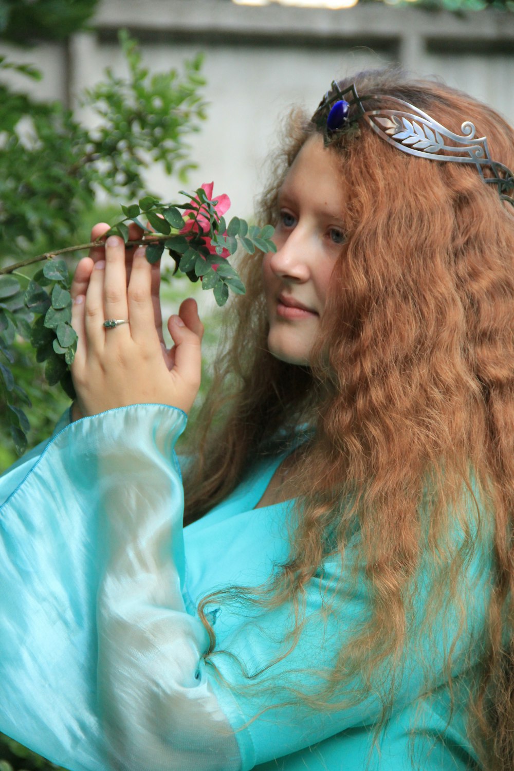 woman in teal shirt holding green plant