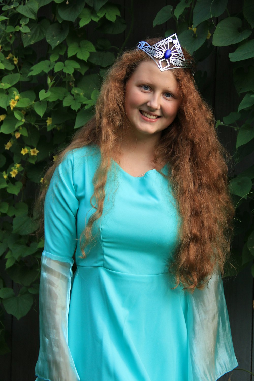 woman in teal long sleeve shirt standing beside green plant