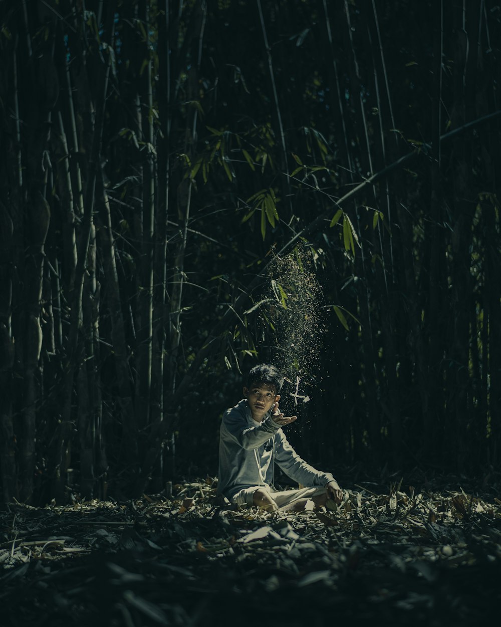 Fille en robe blanche assise sur le sol entourée de plantes de bambou