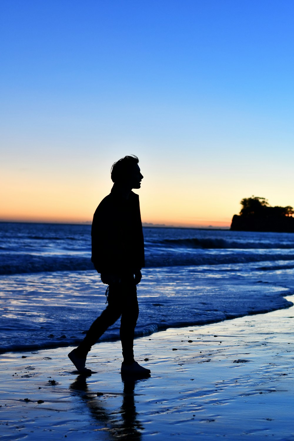 silhouette d’homme debout sur la plage pendant le coucher du soleil