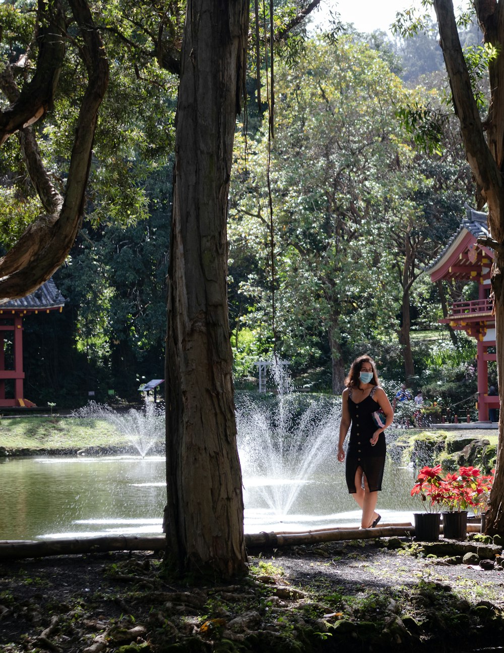 woman in black dress standing on brown wooden bridge over river during daytime