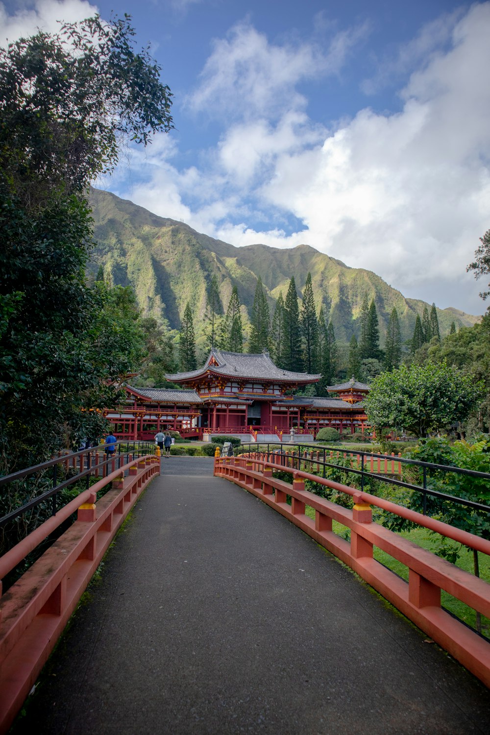 red and brown wooden bridge near green trees and mountain during daytime