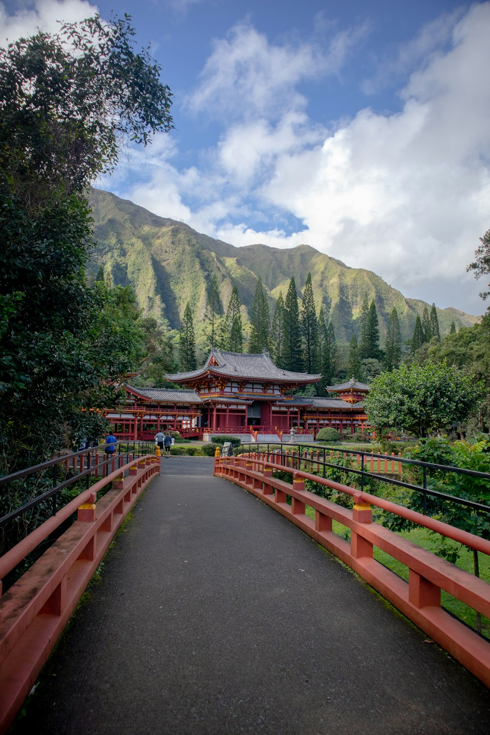 昼間は緑の木々と山の近くにある赤と茶色の木製の橋