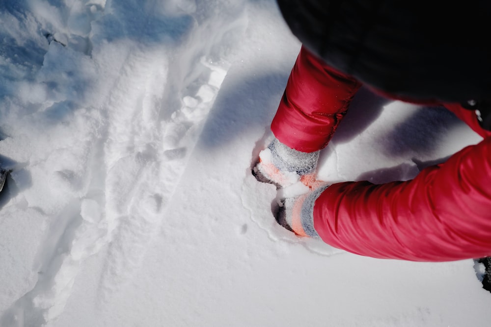 person in red pants and white shoes standing on snow covered ground during daytime