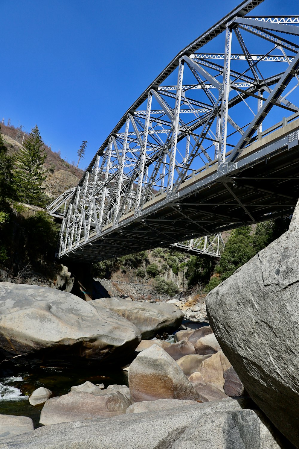 ponte de metal cinzento sobre o rio rochoso