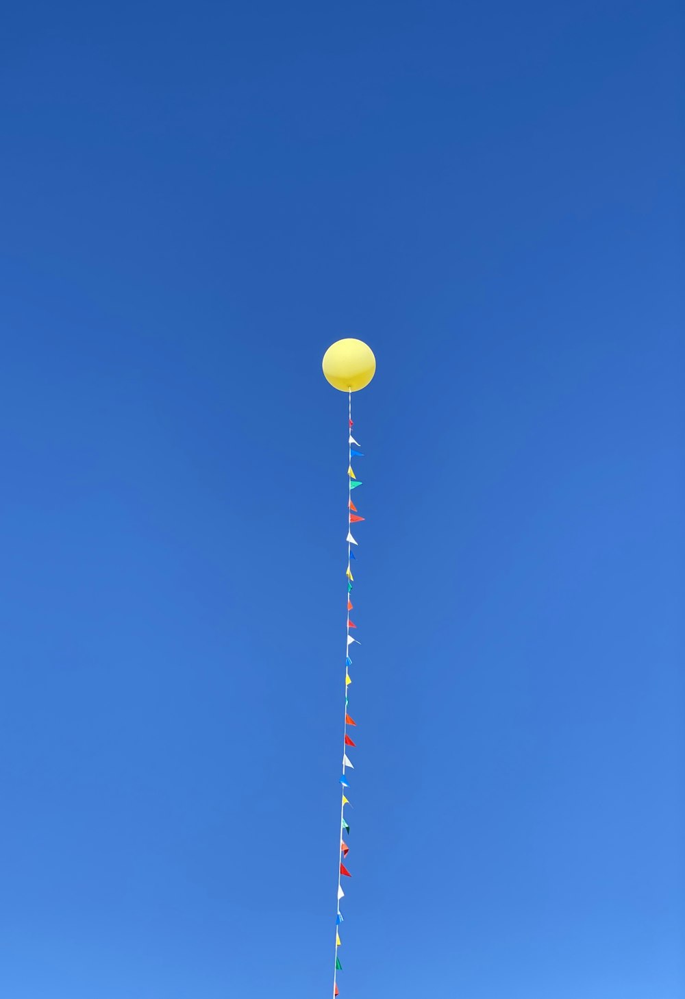 yellow red and white balloons under blue sky during daytime