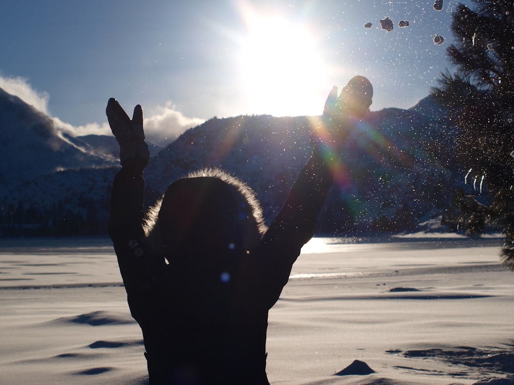 silhouette of man standing on snow covered ground during daytime