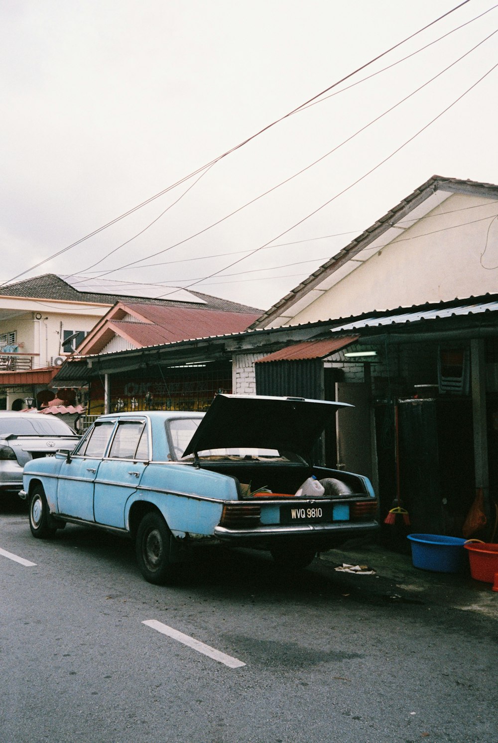 white and black single cab pickup truck parked beside brown wooden house during daytime