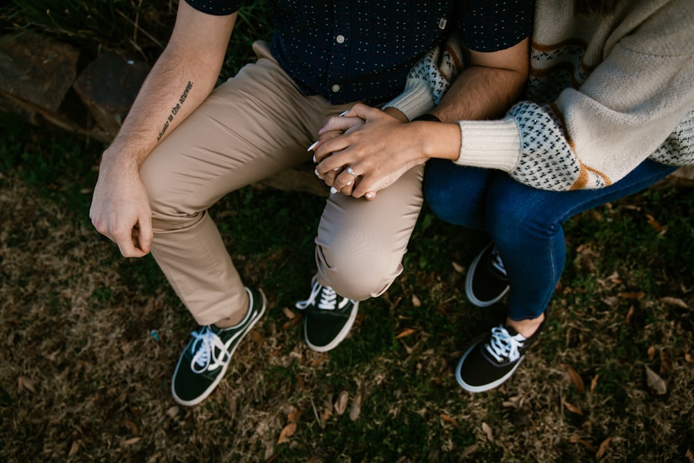 woman in black shirt and blue denim jeans sitting on brown wooden bench