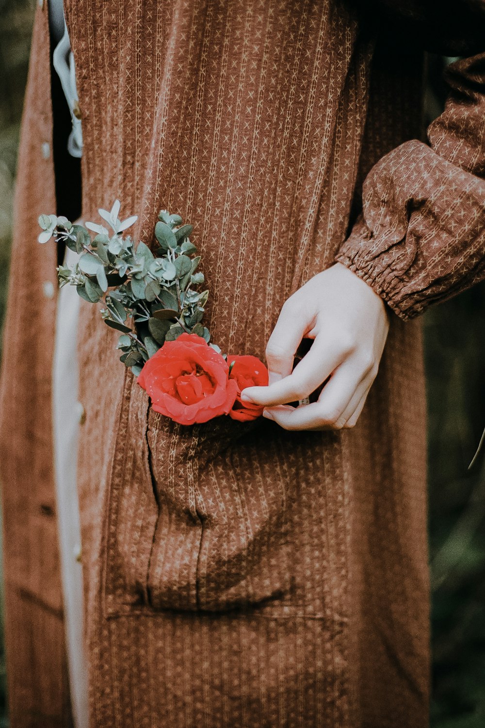 woman in brown long sleeve dress holding red rose bouquet