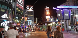 A vibrant neon-lit street corner in Toronto at night, buzzing with energy.