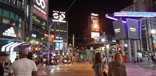 A vibrant neon-lit street corner in Toronto at night, buzzing with energy.