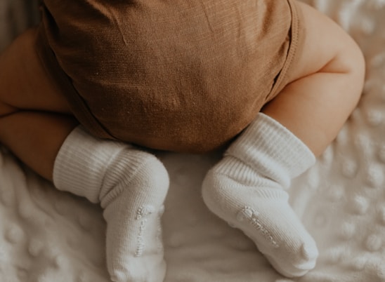 baby in white socks lying on bed