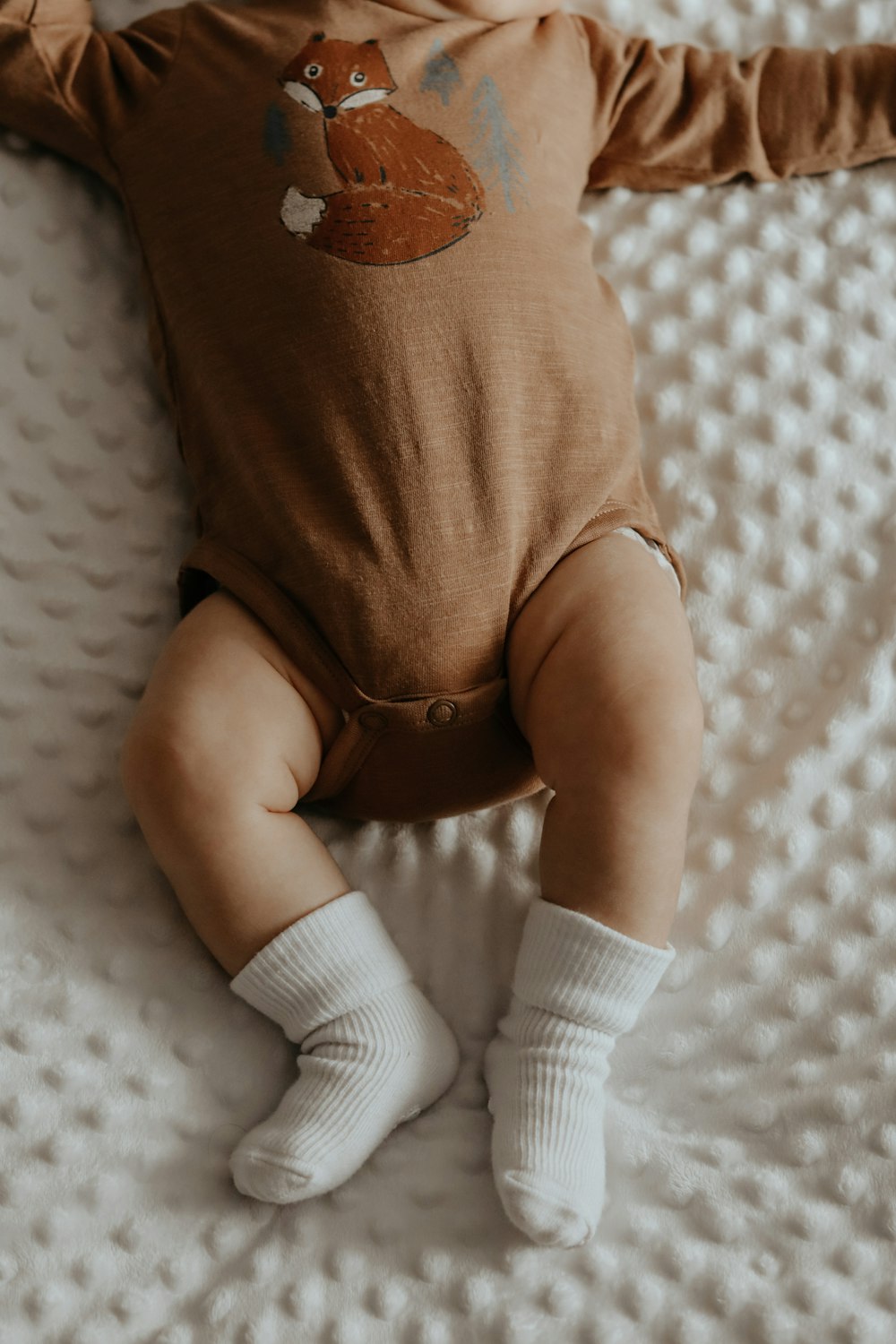 baby in white onesie and white socks