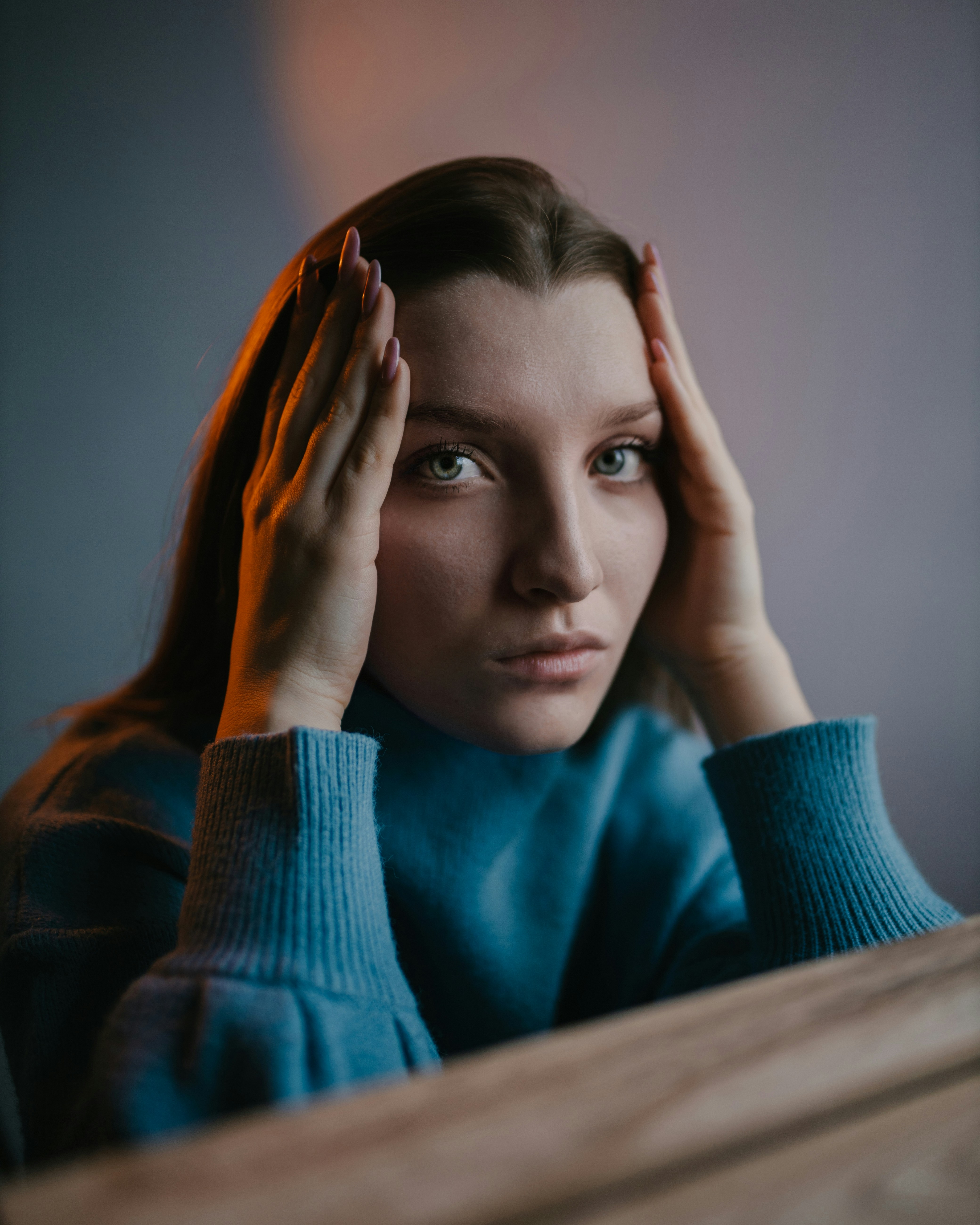 woman in blue knit sweater covering her face