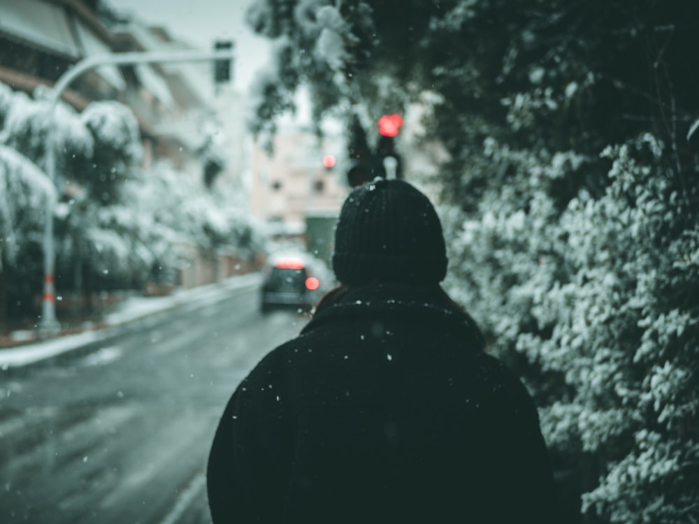 person in black hoodie standing on road during daytime