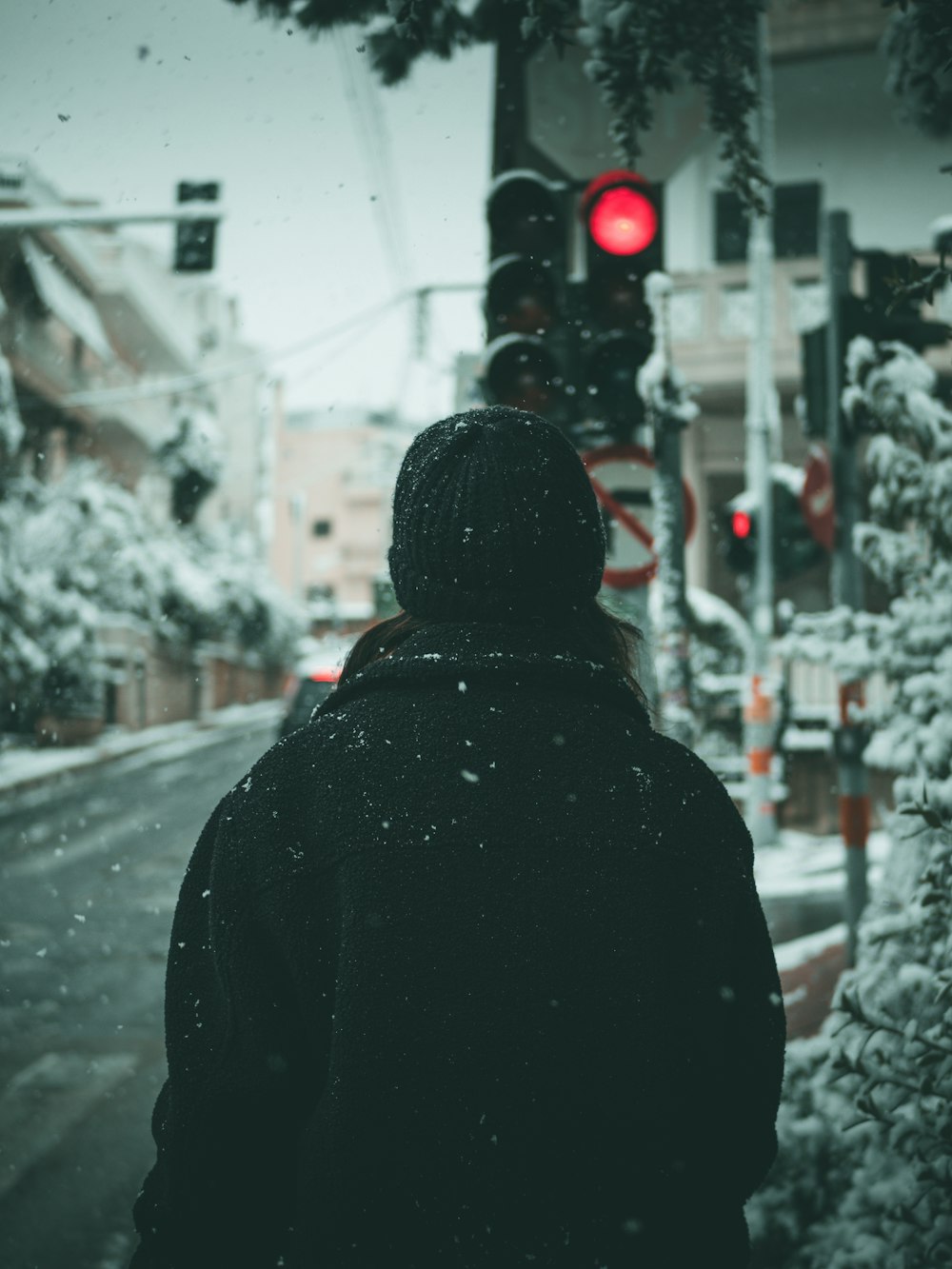person in black hoodie standing on road during daytime