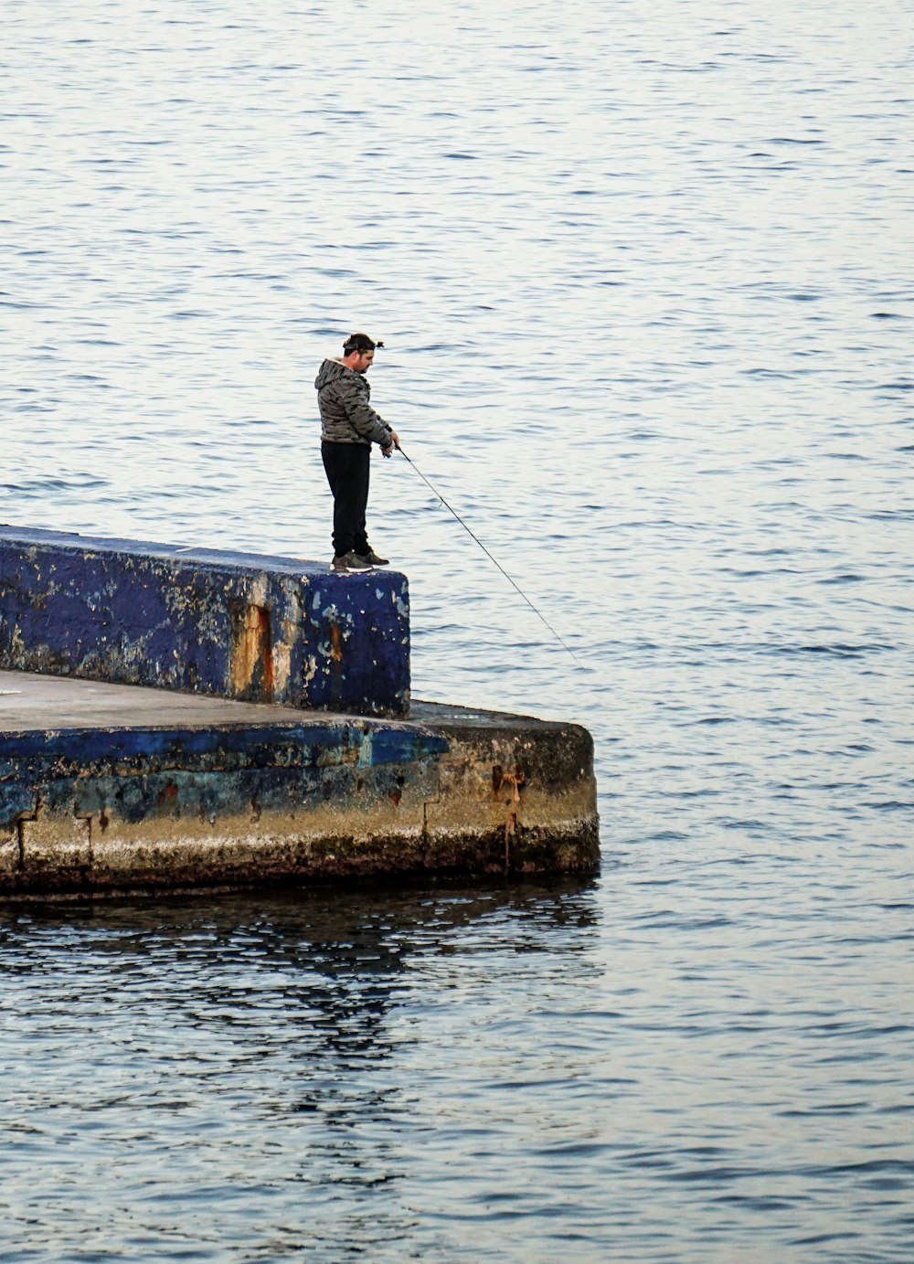 man in black jacket fishing on water during daytime