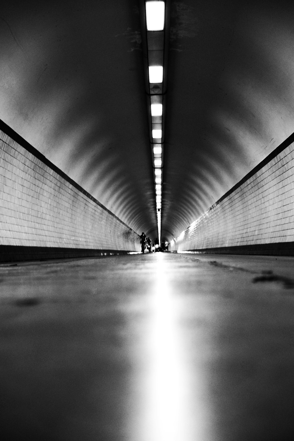 grayscale photo of a man walking on a hallway