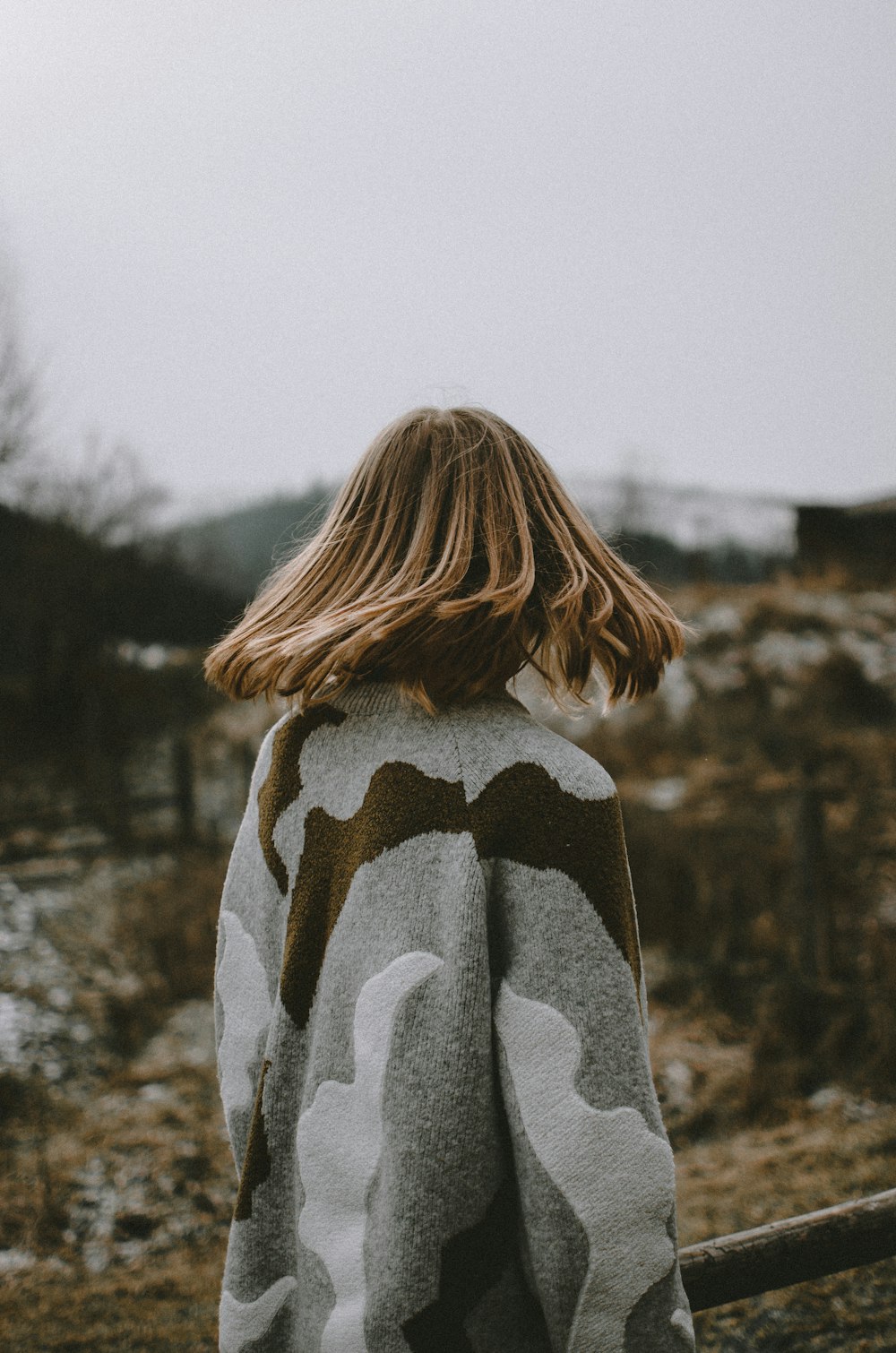 woman in gray and black coat standing near trees during daytime