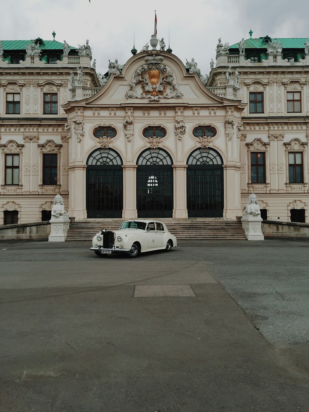 white coupe parked in front of white concrete building during daytime