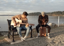 man and woman sitting on bench playing guitar