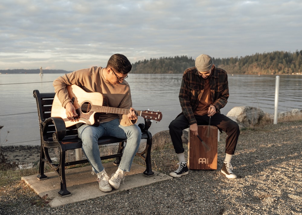 man and woman sitting on bench playing guitar