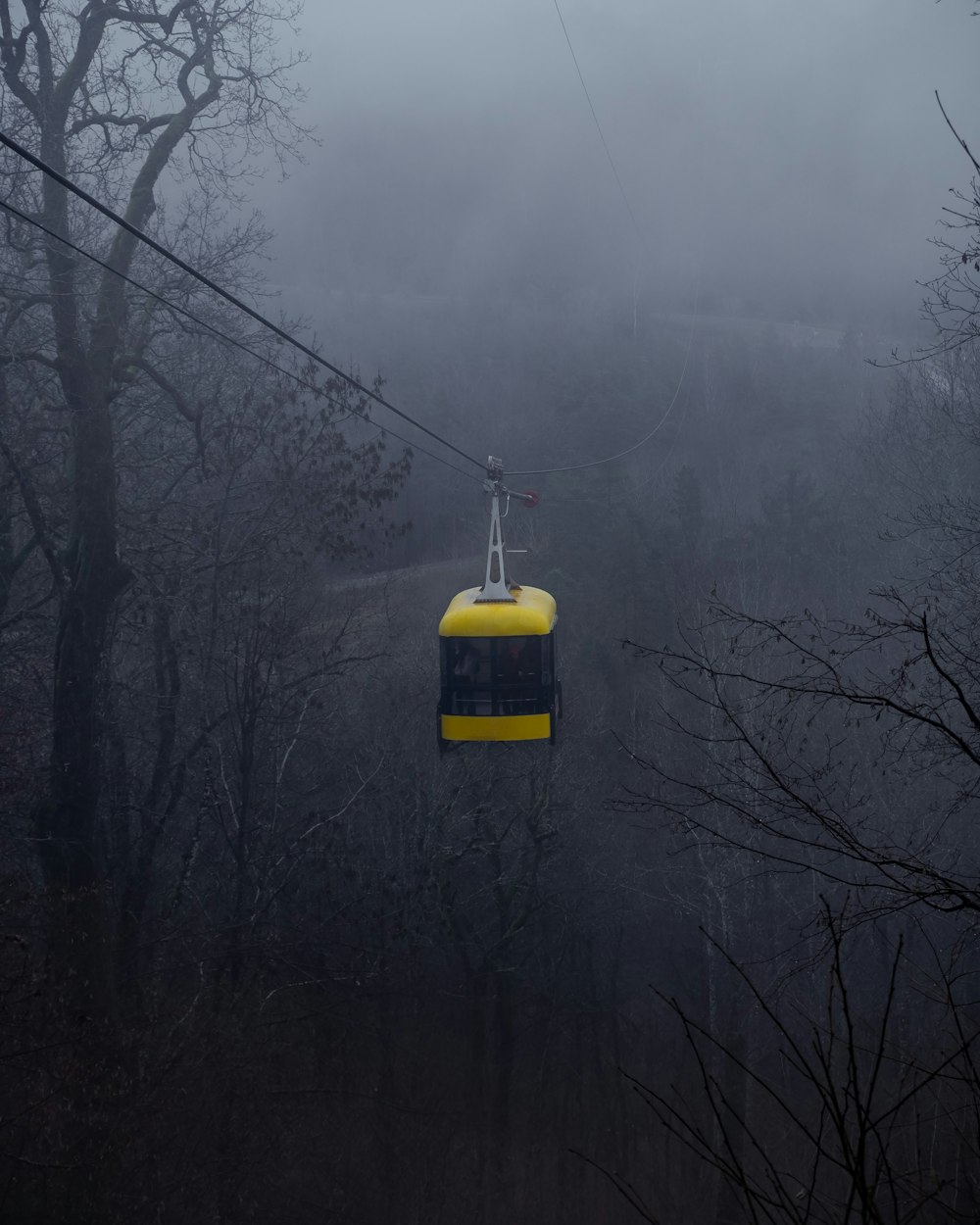 yellow and black cable car over the trees