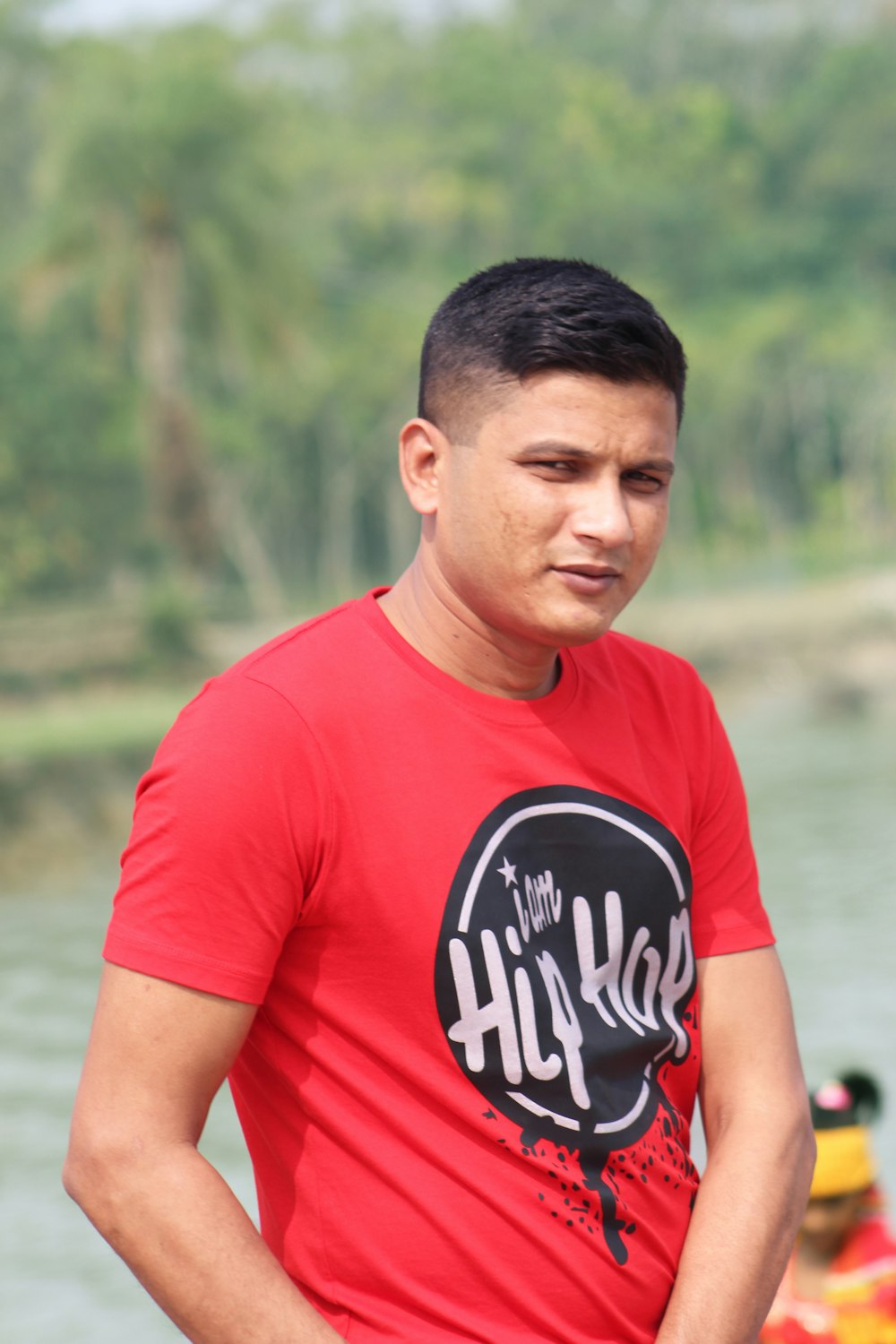 man in red crew neck t-shirt standing near body of water during daytime