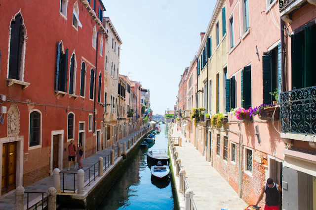 A narrow Dorsoduro canal lined with colorful houses and window flower boxes.