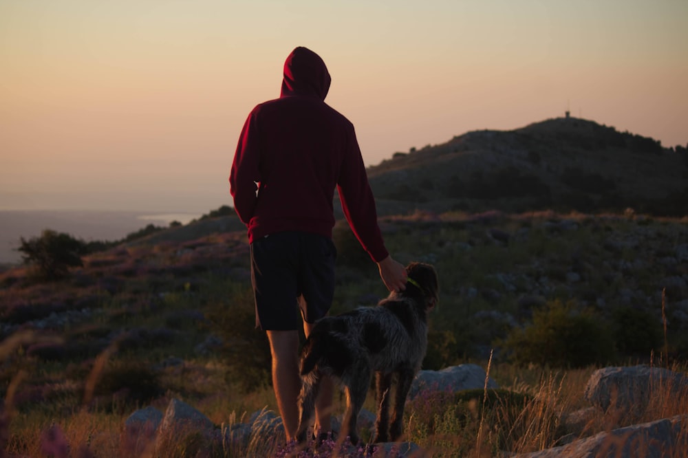 man in red hoodie and black shorts standing on brown grass field with black and white