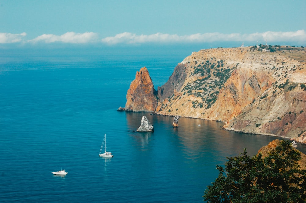 Barca bianca sul mare blu vicino alla montagna marrone durante il giorno
